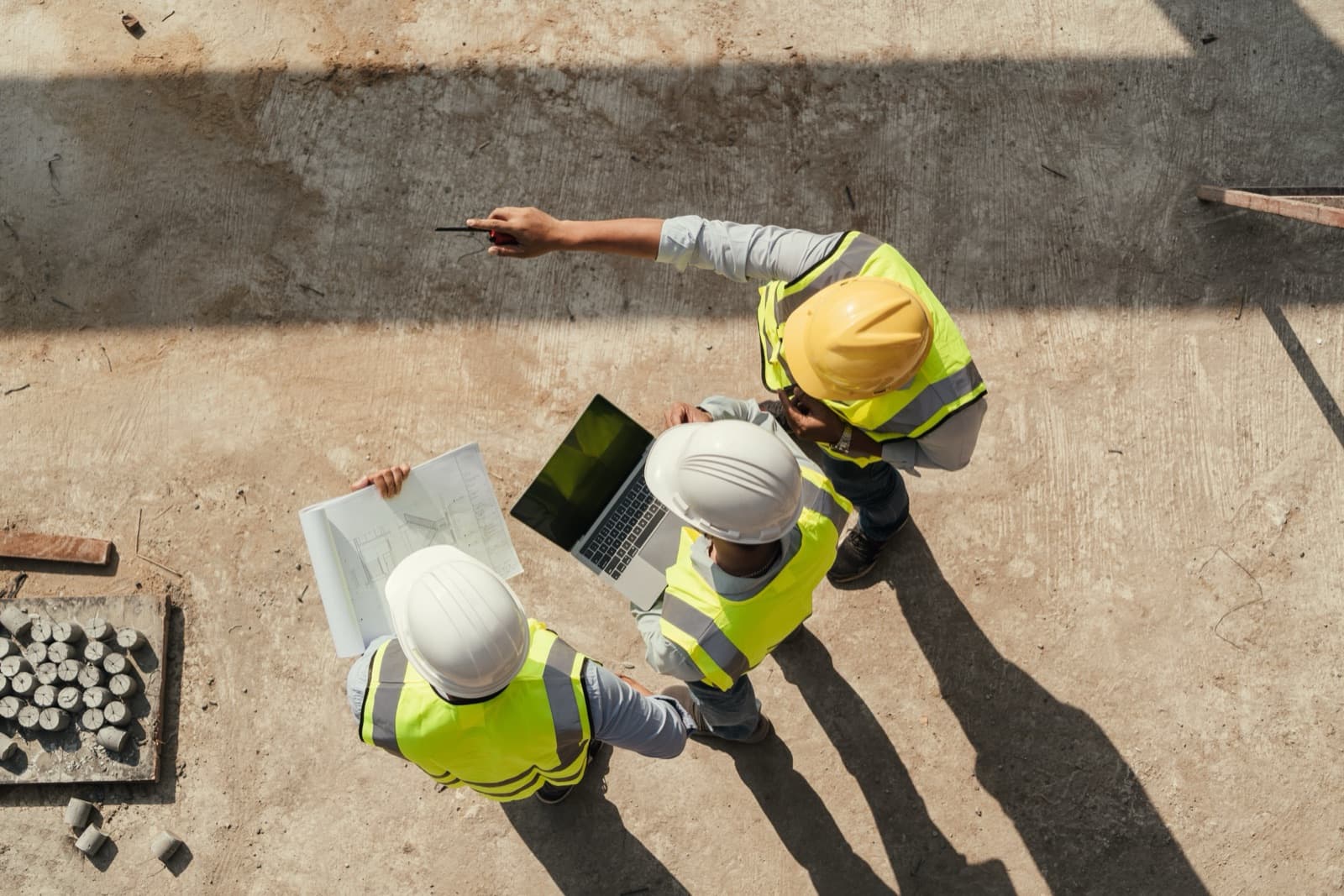 Construction team reviewing project blueprints and a laptop on a job site